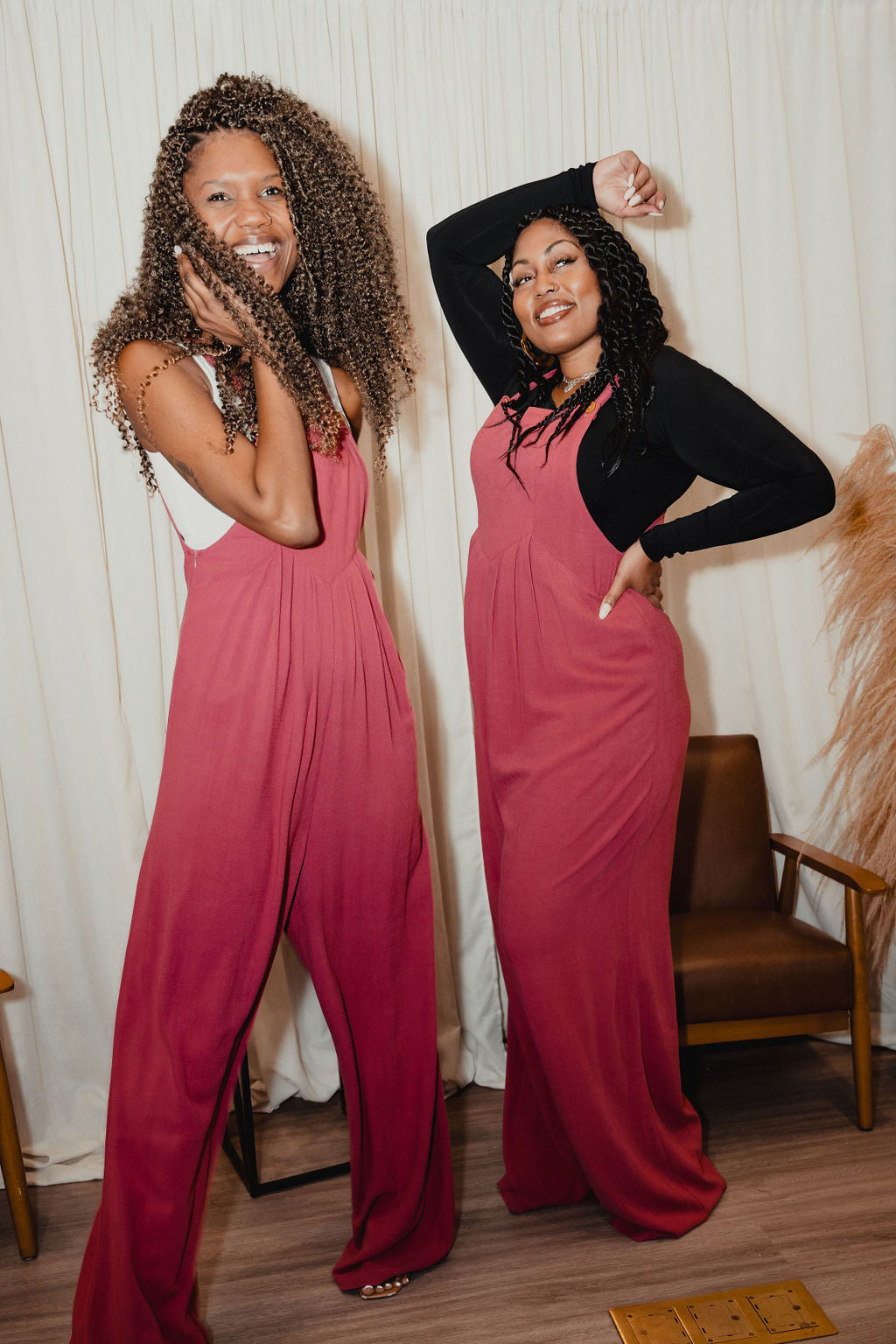 Two tall women smiling in matching berry pink wide-leg jumpsuits—playful, comfy, and full of personality.