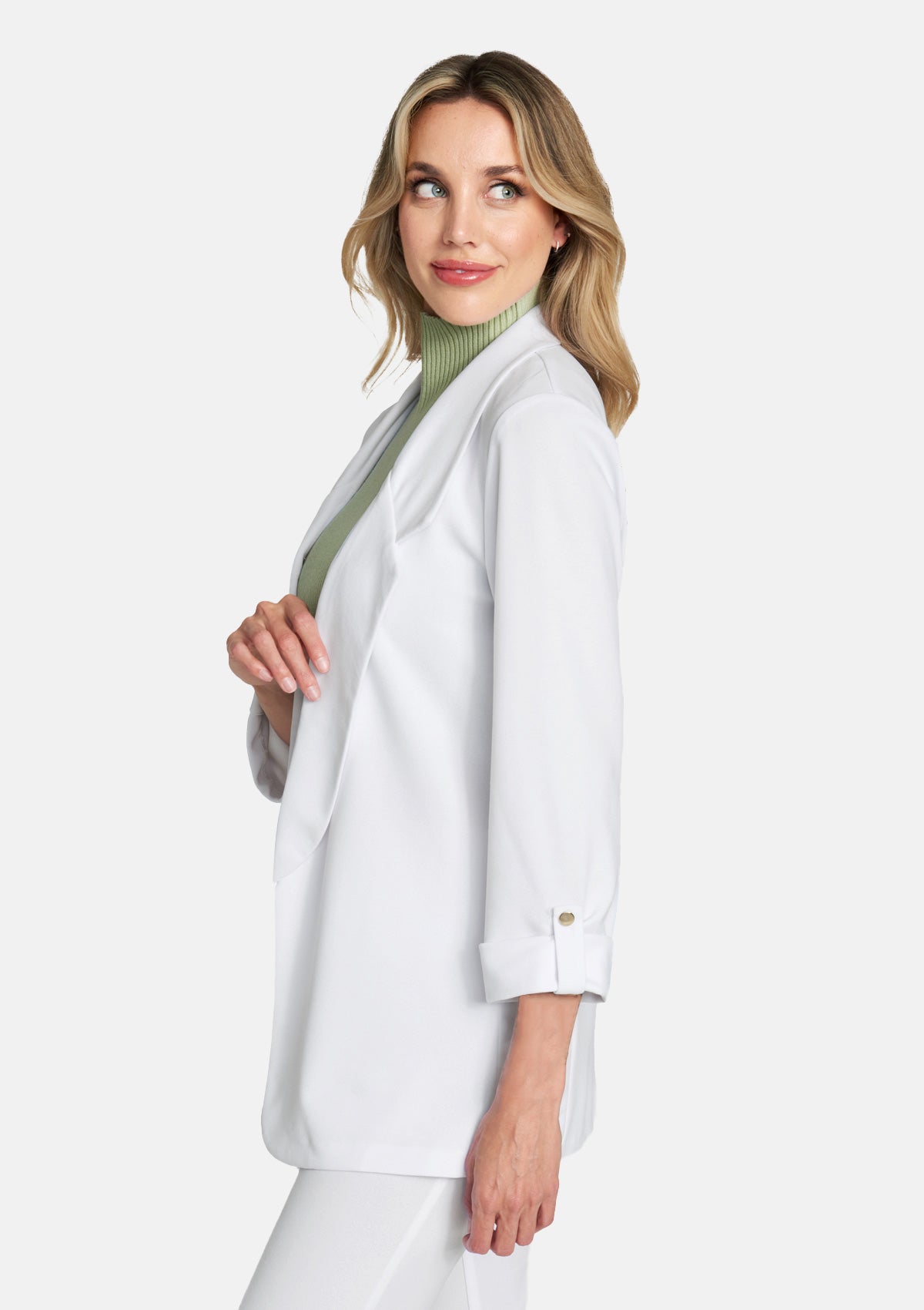 Tall woman wearing a white open-front blazer over a green ribbed turtleneck, styled with white pants.